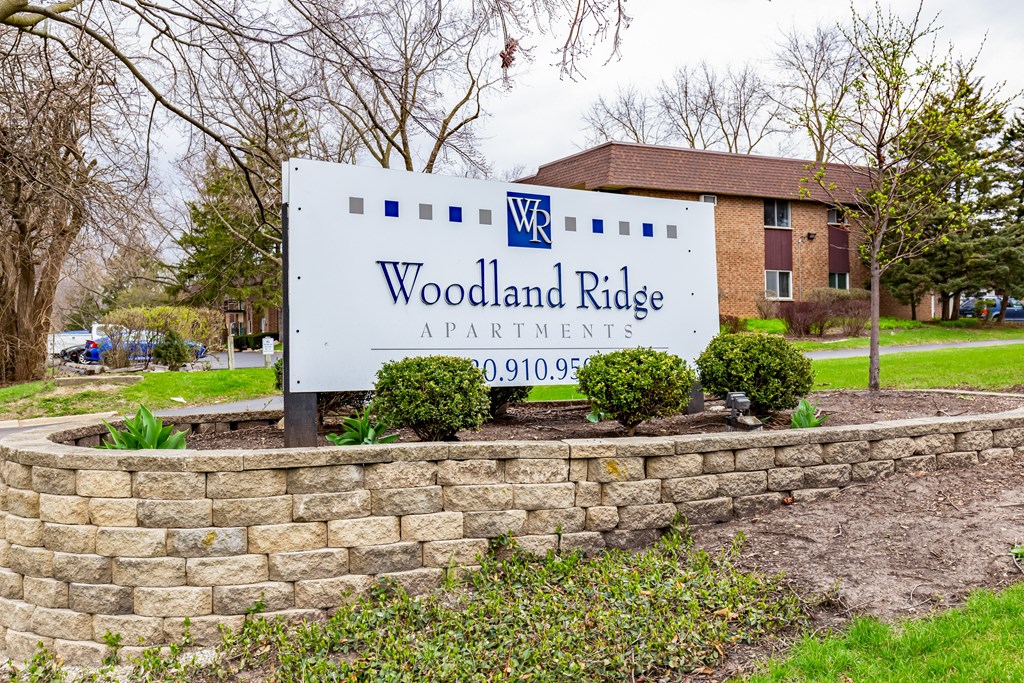A sign for Woodland Ridge Apartments stands in front of a brick building.