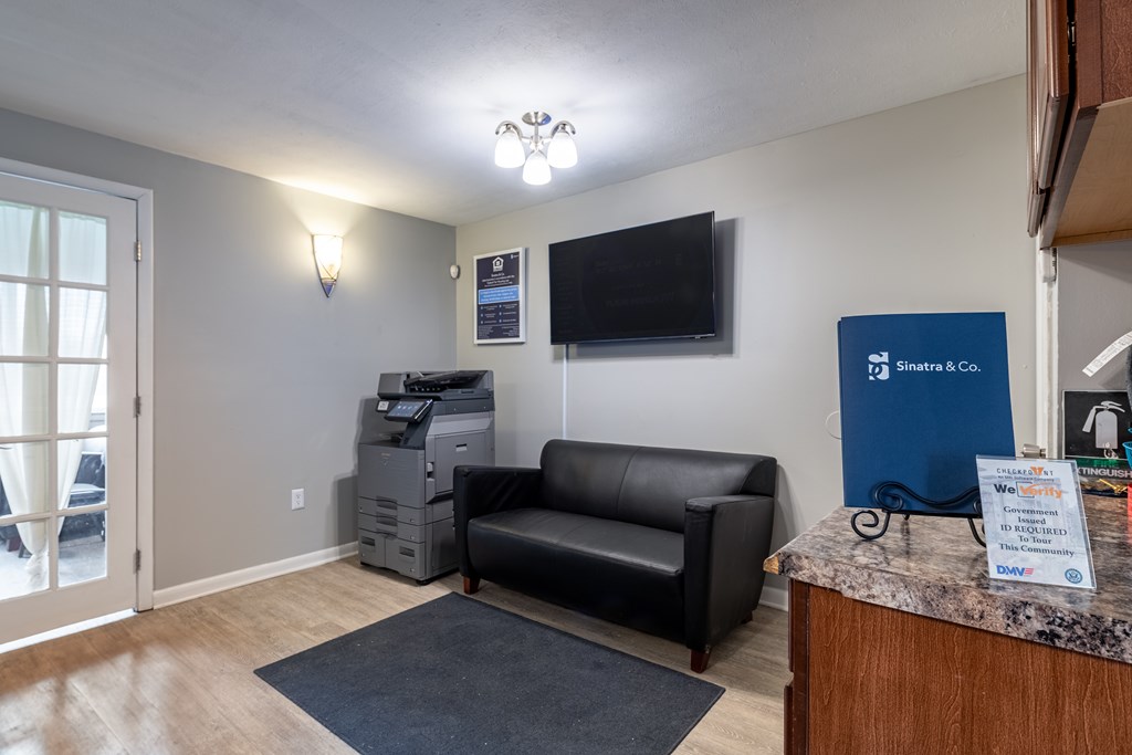 A reception area with a black couch and a blue sign.