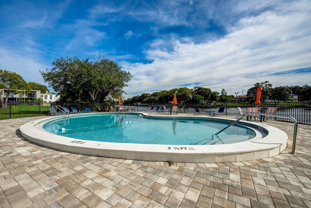 a round swimming pool with a fence and chairs around it