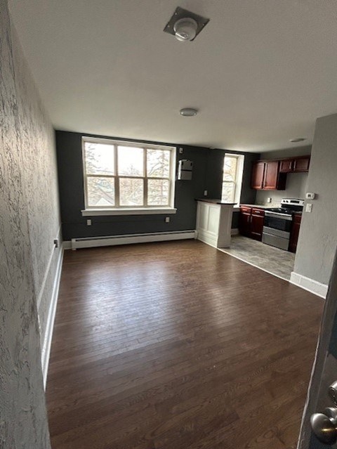 an empty living room with wood floors and a kitchen