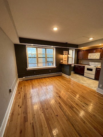 an empty living room and kitchen with wood floors