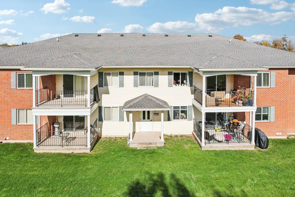 A large house with a grey roof and a green lawn in front.