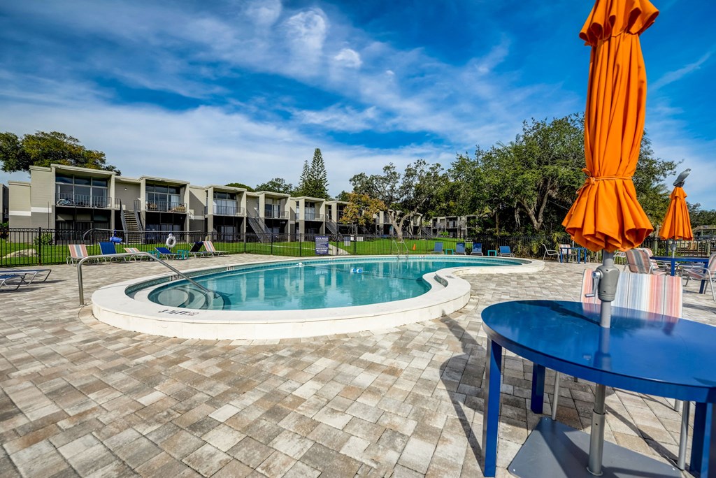 a resort style pool with orange umbrellas and a blue table
