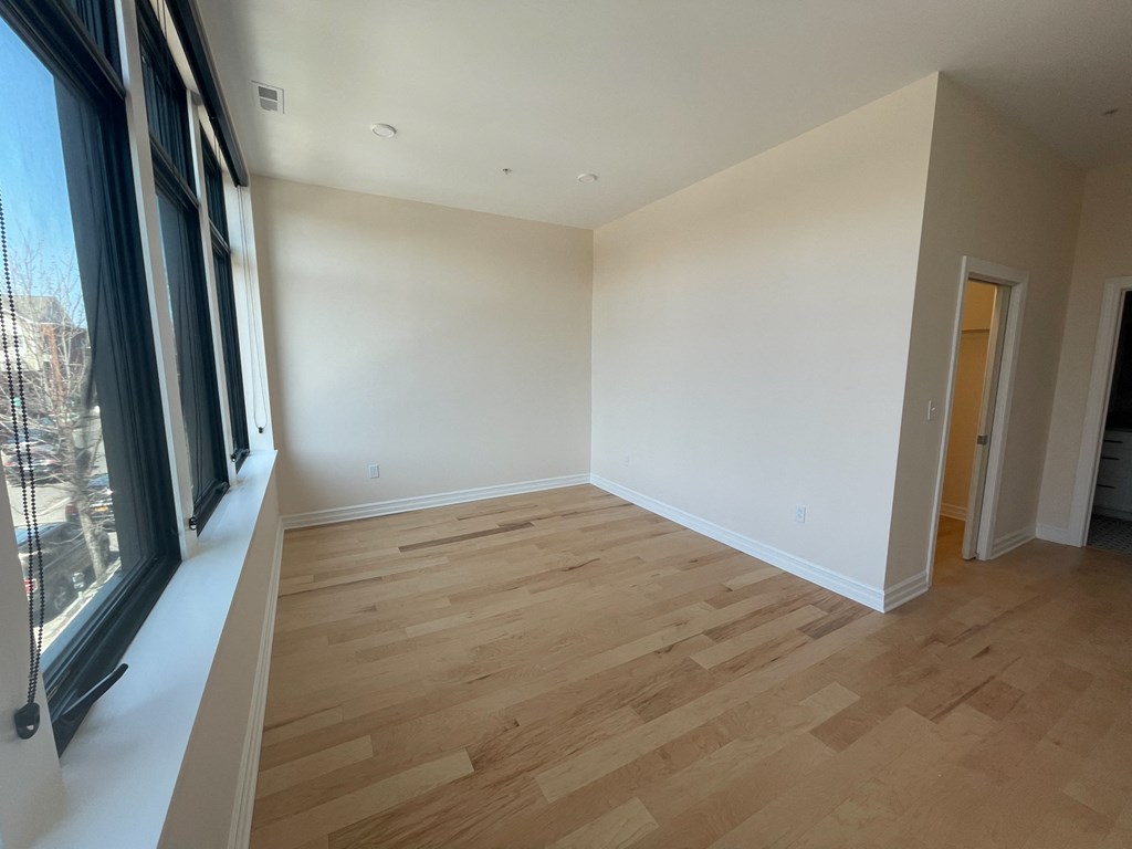 a living room with wood flooring and a large window