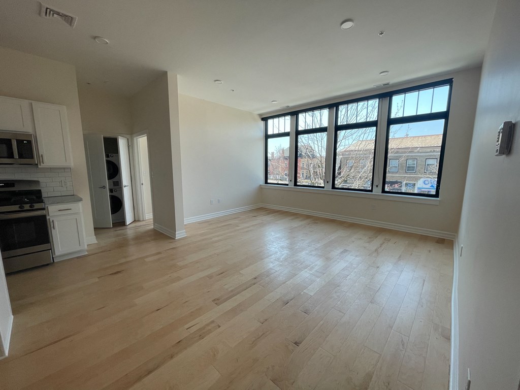 an empty living room with wood floors and a large window
