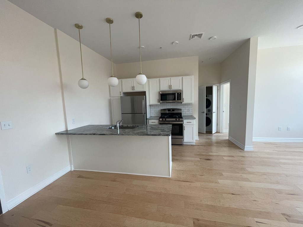 a kitchen and living room with white walls and wood flooring