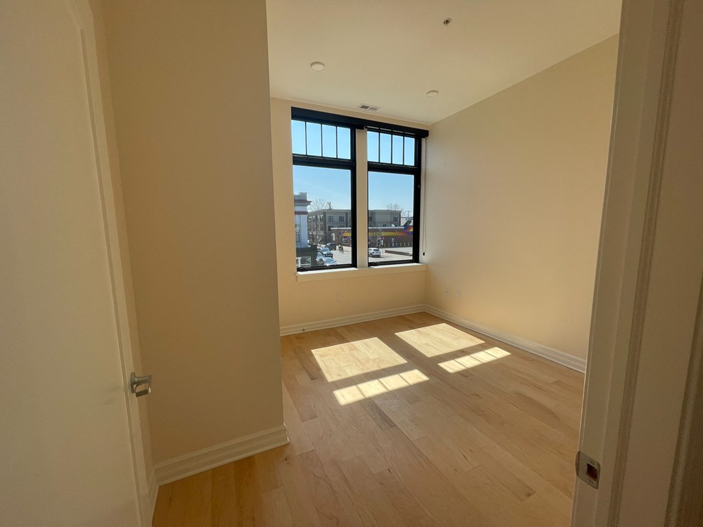 an empty living room with a window and wooden floors
