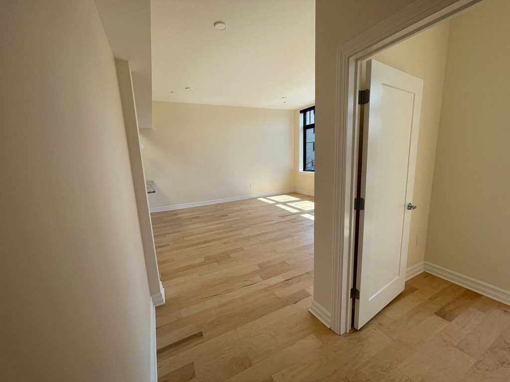 a bedroom and a living room with wood flooring and a door