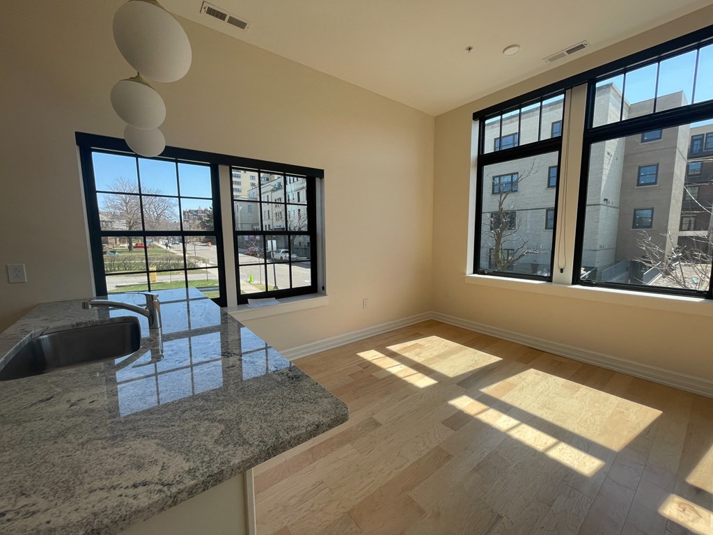 an empty living room with large windows and a granite counter top