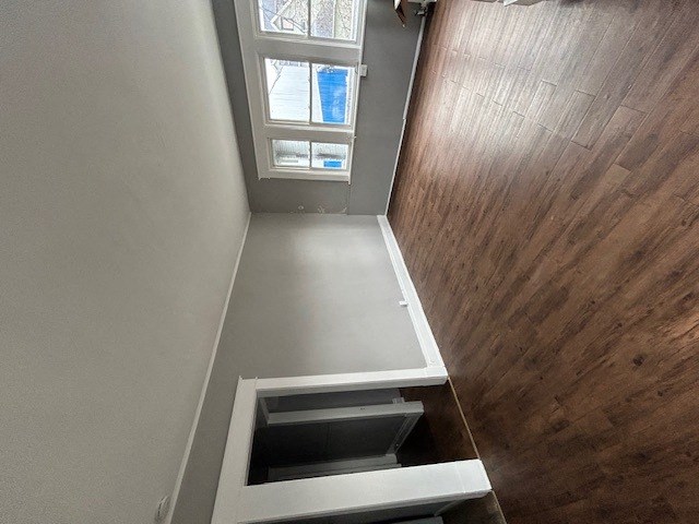a stairwell with a wooden floor and a white staircase with a window