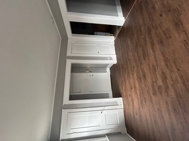 an empty closet with drawers and shelves and a wood floor