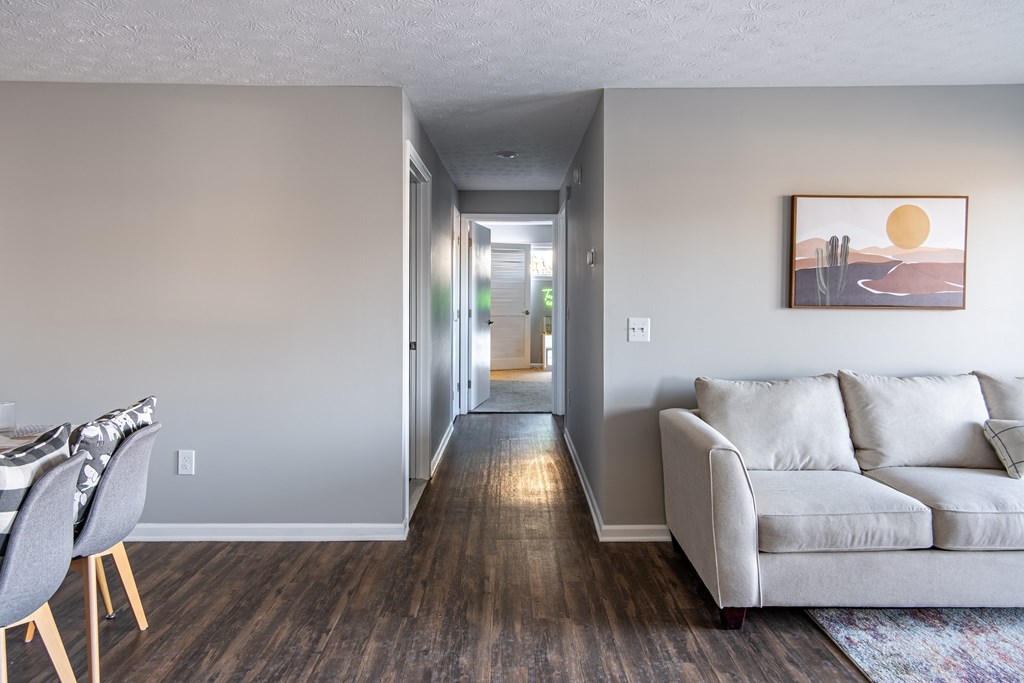 A living room with a grey couch and a painting of a sunset on the wall at Centerpointe Apartments, Canandaigua, NY, 14424