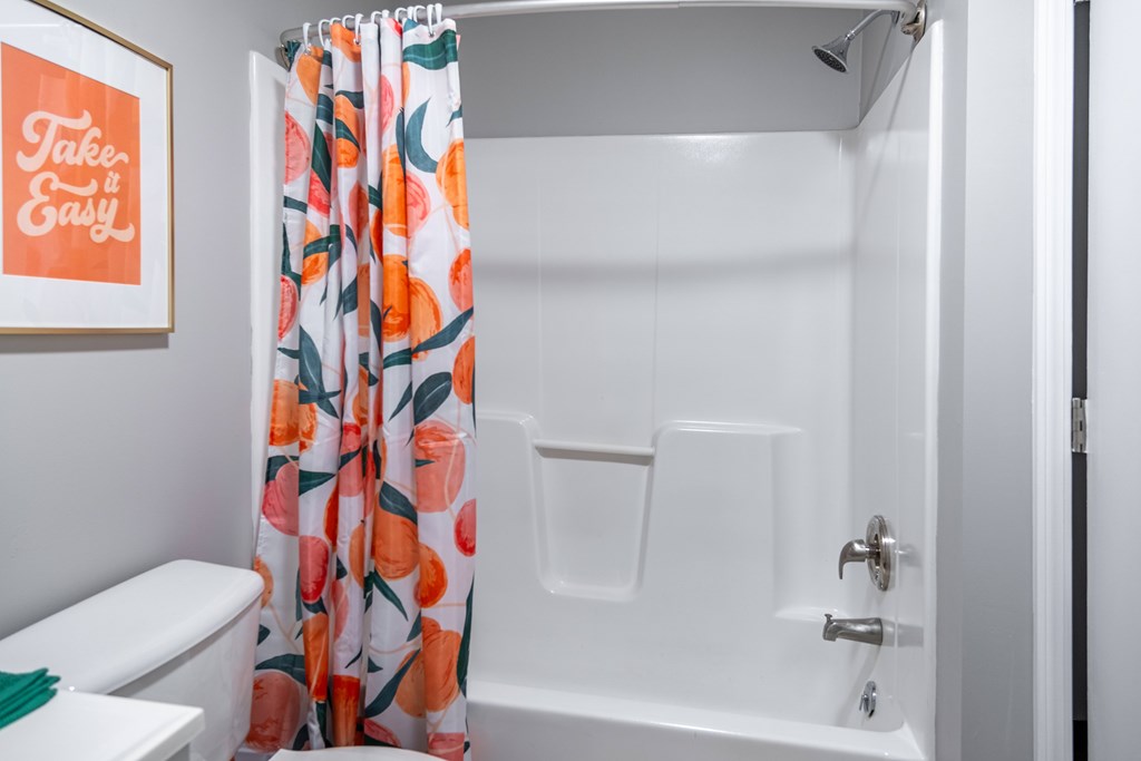 A white bathroom with a shower curtain and a toilet at Centerpointe Apartments, Canandaigua, NY