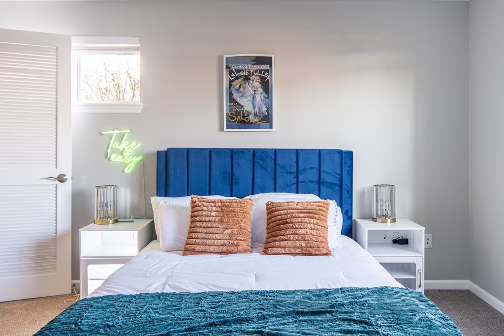 A bedroom with a large bed and a blue headboard at Centerpointe Apartments, Canandaigua, NY