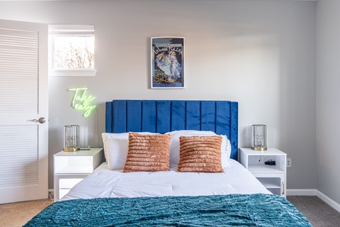 A bedroom with a large bed and a blue headboard at Centerpointe Apartments, Canandaigua, NY