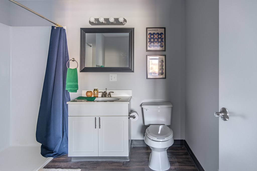 A bathroom with a white toilet and a blue shower curtain at Centerpointe Apartments, Canandaigua, New York