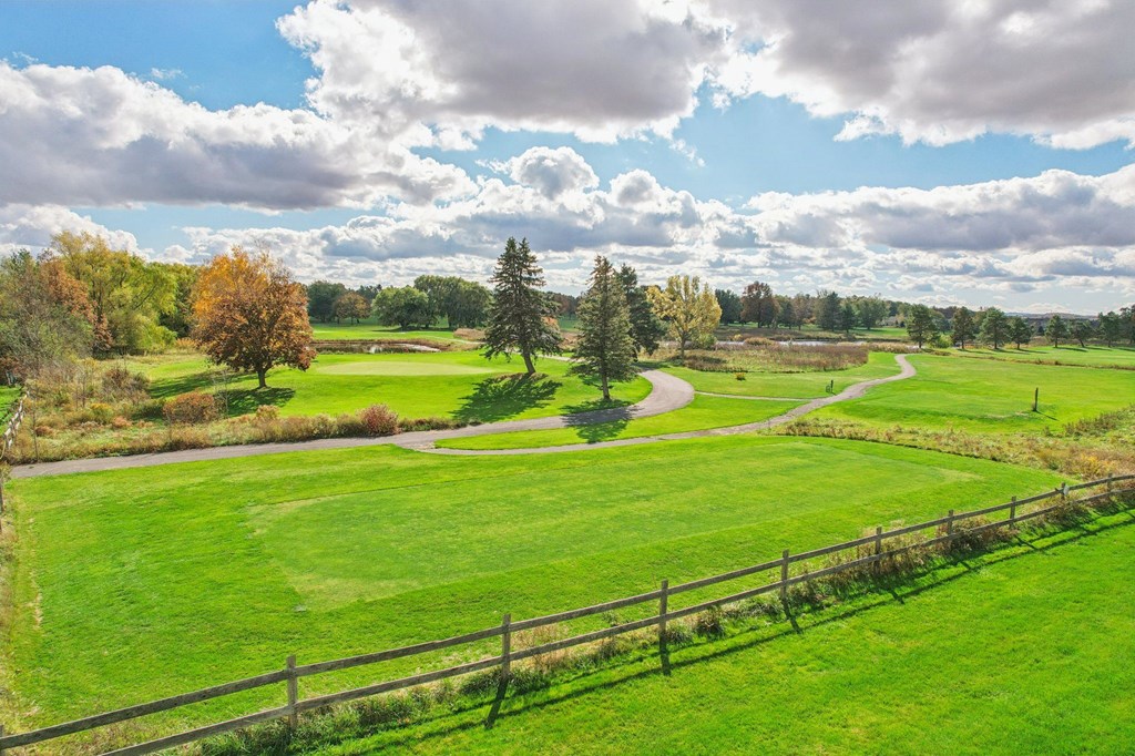 A beautiful landscape with a fence in the foreground and a winding path in the distance.