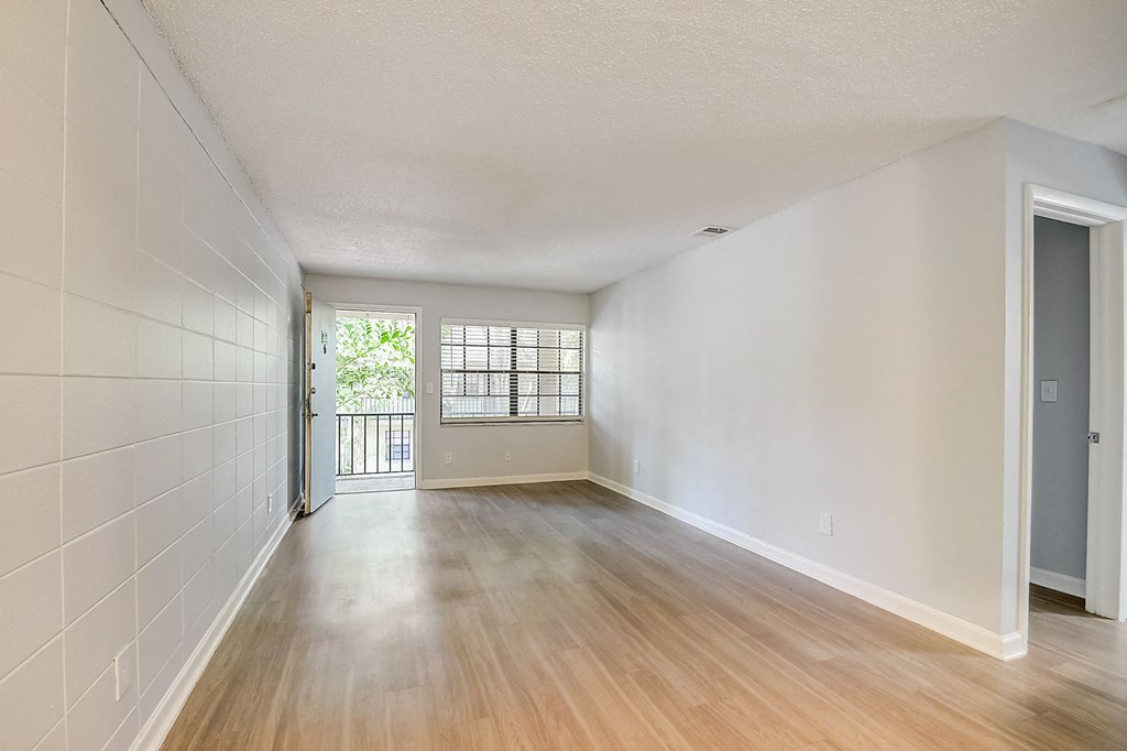 an empty living room with wood flooring and a door to a balcony at Fernwood Grove Apartments at 4900 MacDill Ave in Tampa, Florida