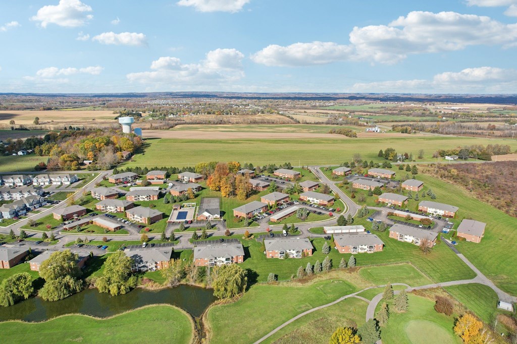 A bird's eye view of a residential area with houses and a pond.