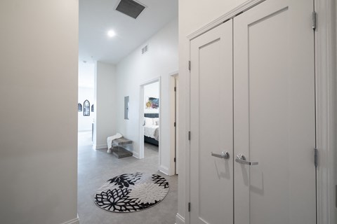 A hallway with a rug and a bedroom with a bed and a dresser.at The Annex Apartment, Buffalo, NY