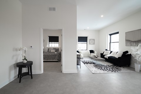 A living room with a black couch and a small table with a vase of flowers on it.