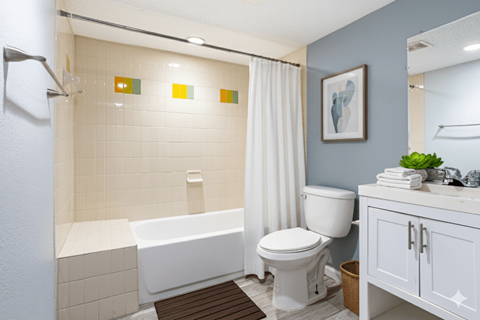 A white bathtub with a shower head and a white toilet in a bathroom.
