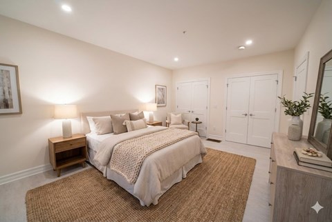 A bedroom with a bed, nightstand, and a mirror.