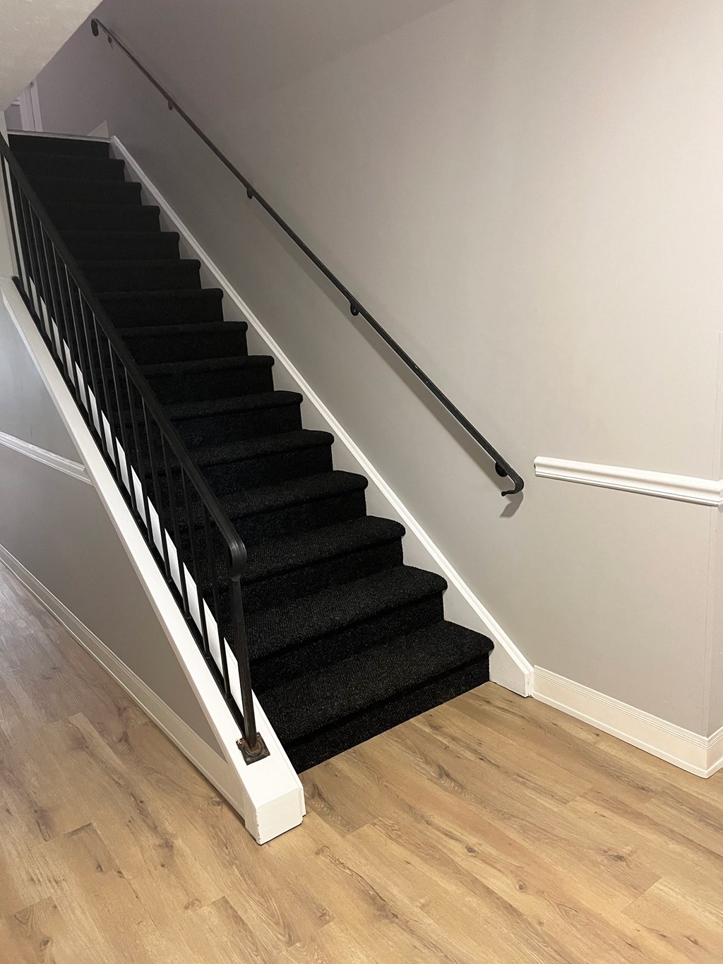a black carpeted stairway with a metal railingat Centerpointe Apartments, Canandaigua