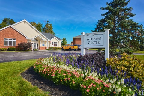 the welcome center sign in front of a building with flowers at Centerpointe Apartments, New York, 14424