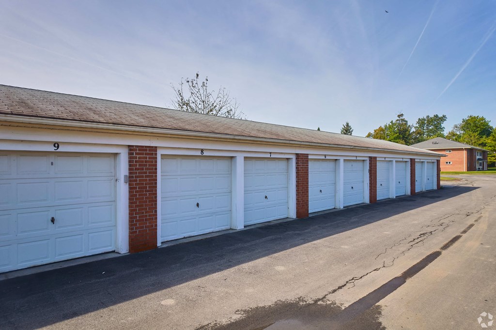 a row of garages with blue garage doors and brick at Centerpointe Apartments, Canandaigua, NY