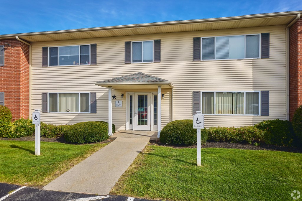 the front of an apartment building with a walkway and two parking signs at Centerpointe Apartments, Canandaigua, New York