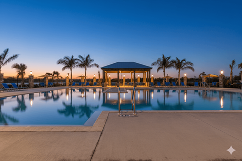 A gazebo is situated in the middle of a pool with palm trees in the background.