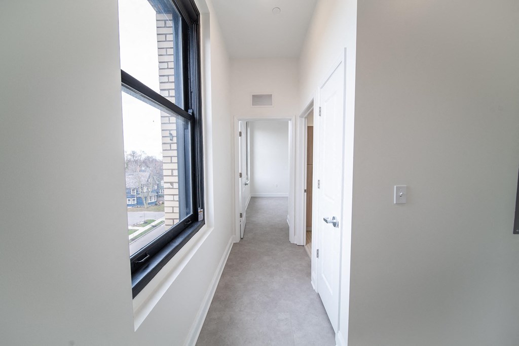 a hallway with a large window and a door into a house