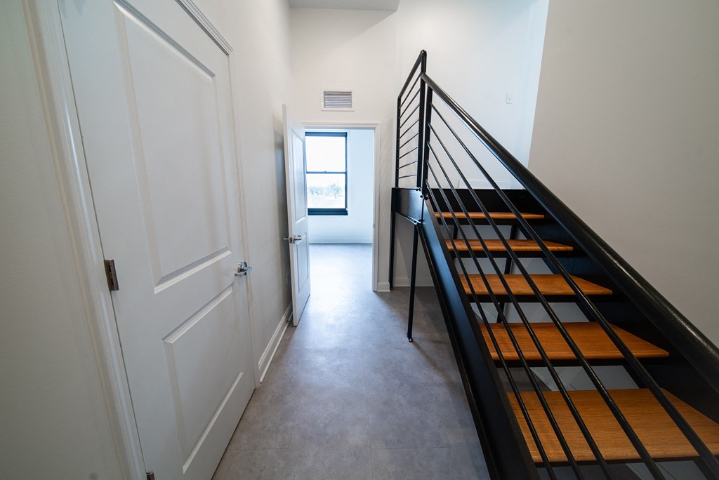a hallway with a staircase and a white door and a door to a white room