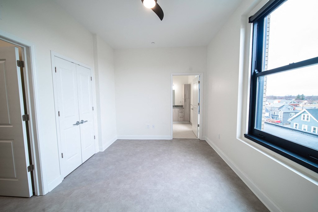 an empty bedroom with a large window and a door to a bathroom