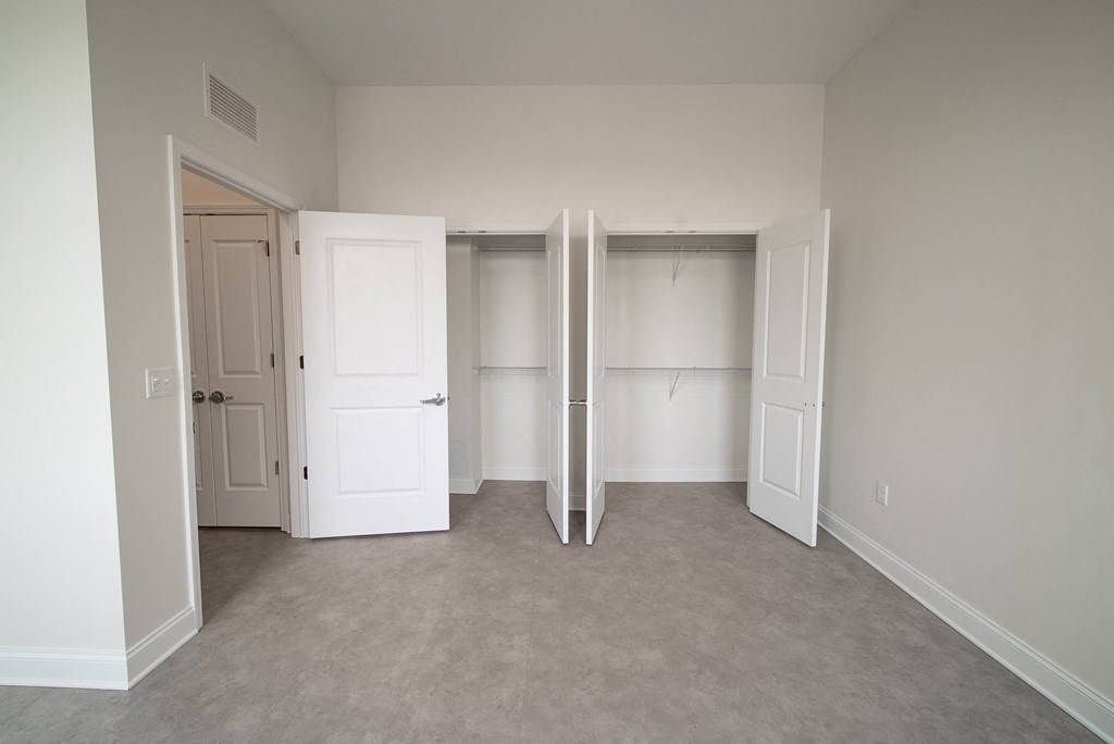 an empty bedroom with two closets and three doors