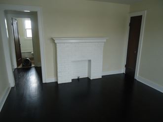a living room with a white brick fireplace and wooden floors