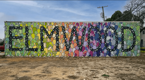 A large, colorful mosaic spelling out "ELMWOOD" stands in a field.