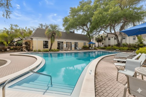 A swimming pool surrounded by lounge chairs and trees.