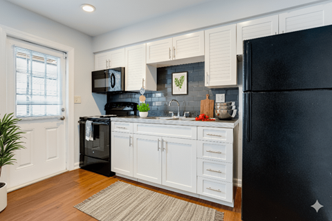 A kitchen with black appliances and white cabinets.