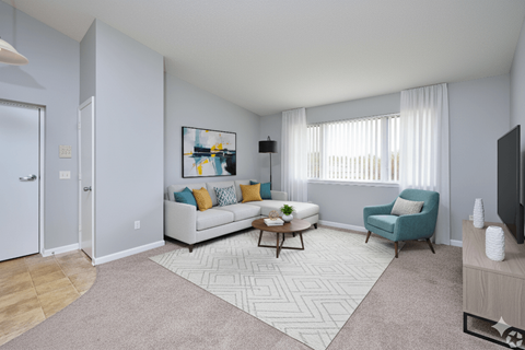 A living room with a white couch, a coffee table, a blue armchair, and a painting on the wall.
