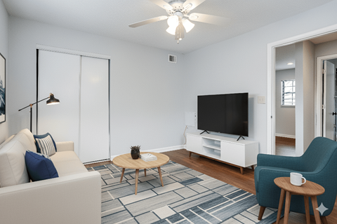 A living room with a white couch, a coffee table, a television, and a blue chair.