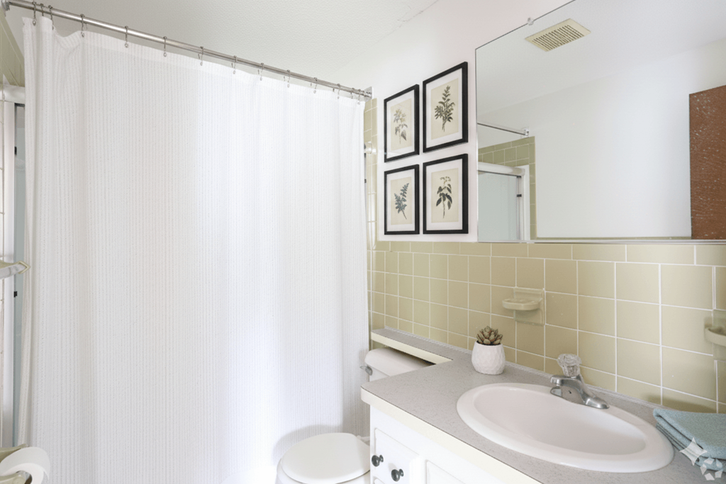 A white bathroom with a toilet, sink, and shower curtain.