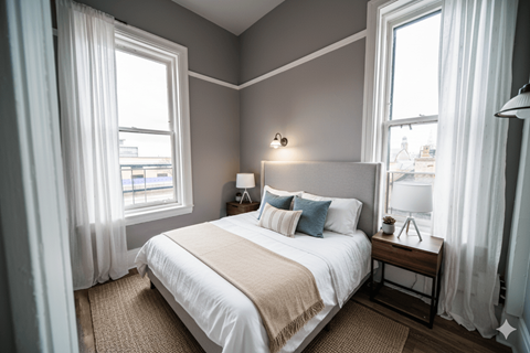 A bedroom with a large bed and two windows.