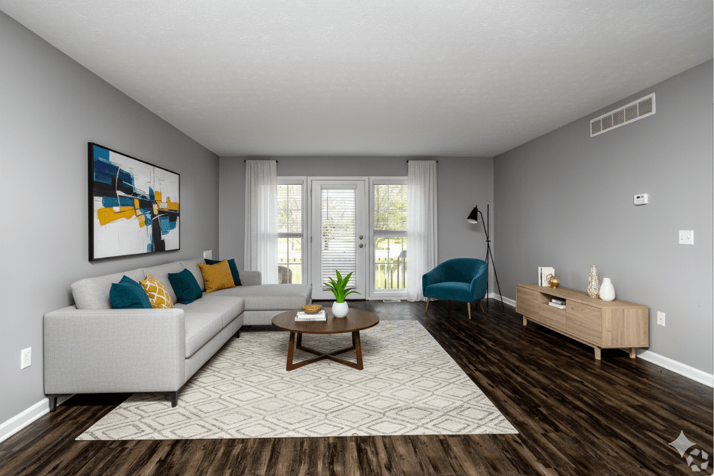 A living room with a grey couch, a blue chair, a coffee table, and a painting on the wall.