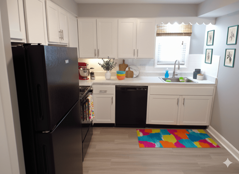 A black refrigerator is in a kitchen with white cabinets.