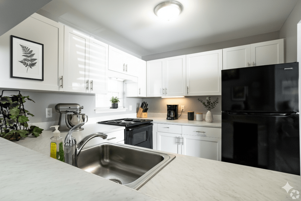 A modern kitchen with black appliances and white cabinets.