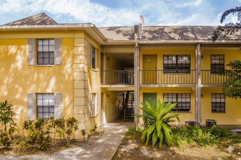 A yellow building with a green door and windows.