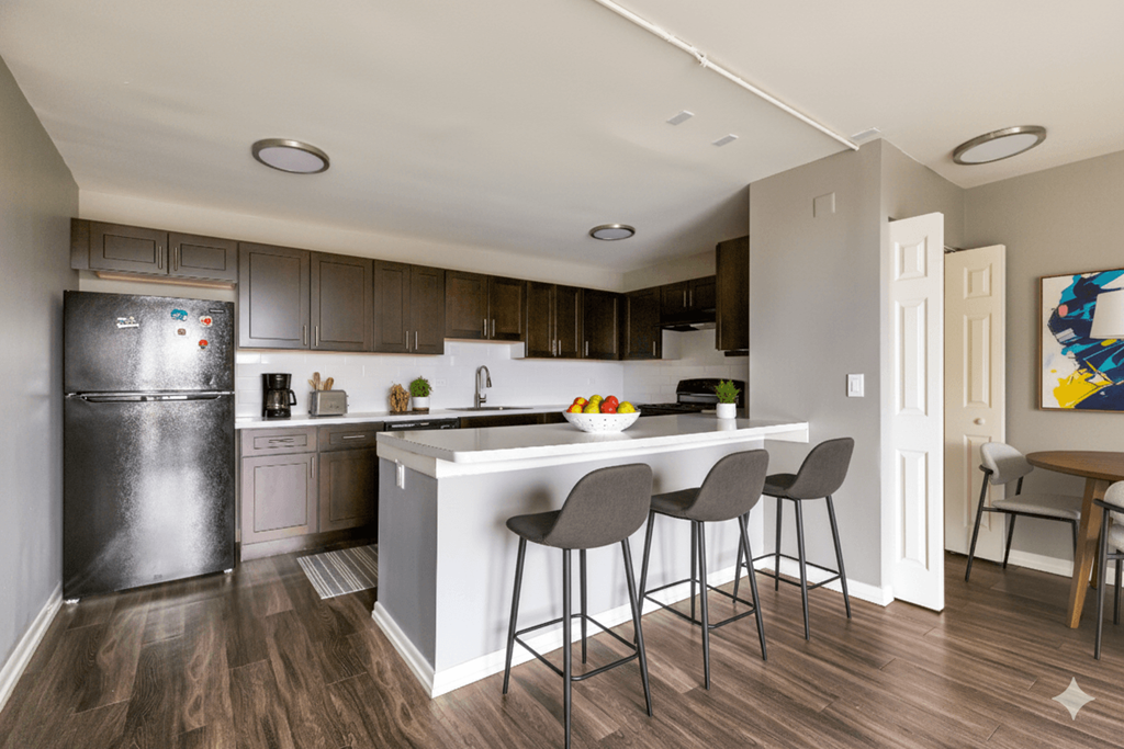 A kitchen with a white island and grey bar stools.