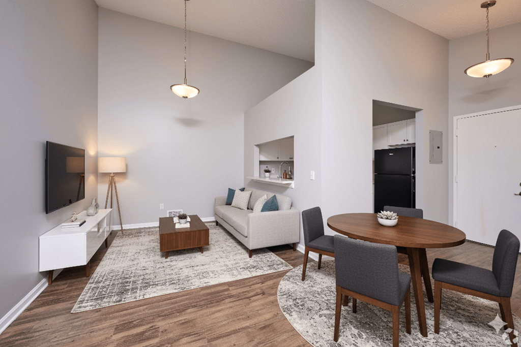 A modern living room with a wooden table and grey chairs.